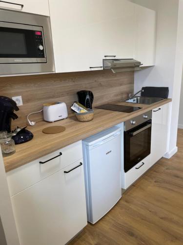 une cuisine avec des armoires blanches et un comptoir en bois dans l'établissement Portet - Appartement 1, à Portet-sur-Garonne