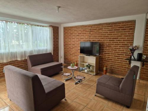 a living room with couches and a brick wall at Casa Flores de la Montaña in Mineral del Monte