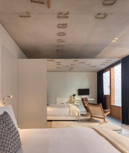 a bedroom with a bed and a chair and a television at Hotel Tipografia do Conto by Casa do Conto in Porto