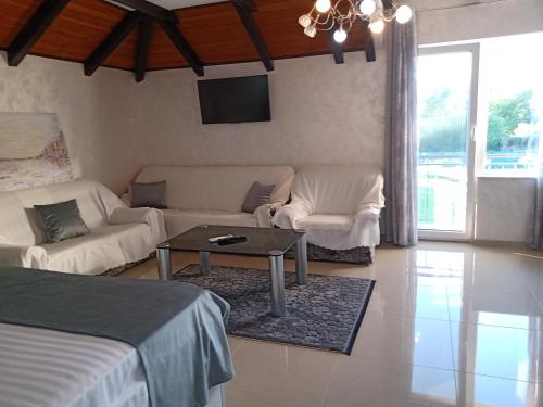 a living room with a bed and a couch and a table at Moravska Obala - Prenoćište i Restoran in Velika Plana