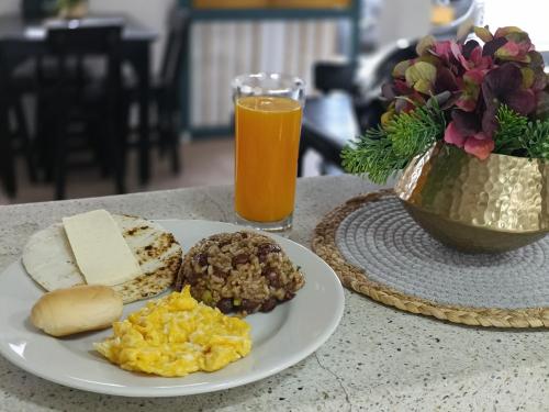 a plate of breakfast food and a glass of orange juice at Colina del Sol Hotel Hacienda in Quimbaya