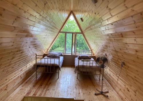 a room with two beds in a round room with a window at QubAframe in Digah