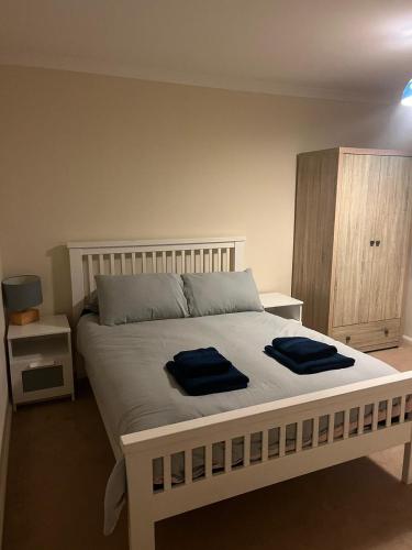 a bedroom with a bed with two blue towels on it at Milton Keynes Comfort Haven in Haversham