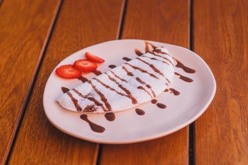 a piece of cake on a plate with strawberries at Pousada Arraial Inn in Arraial do Cabo