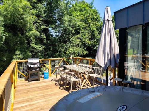 a deck with a table and an umbrella and a grill at Marie à la Campagne in Dolembreux