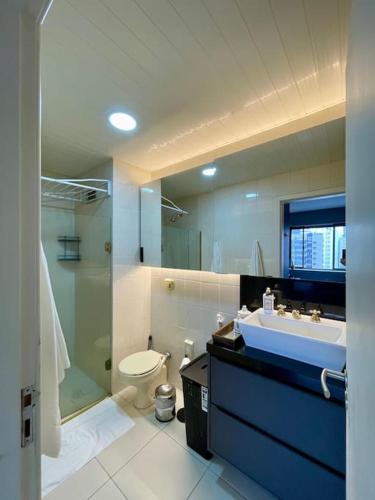 a bathroom with a sink and a toilet and a mirror at Apto aconchegante no Hotel Mercure in Joinville