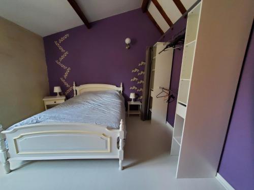 a bedroom with a white bed and purple walls at Gîte des peupliers, gîte à la ferme in Rebergues