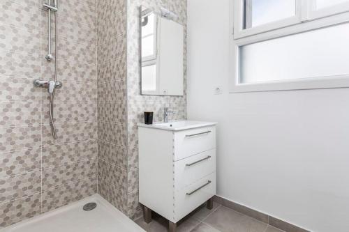 une salle de bain blanche avec un lavabo et une douche dans l'établissement Portet - Charmant T3, à Portet-sur-Garonne