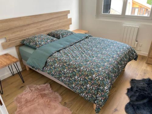 une chambre avec un lit avec une couette fleurie dans l'établissement Portet - Charmant T3, à Portet-sur-Garonne