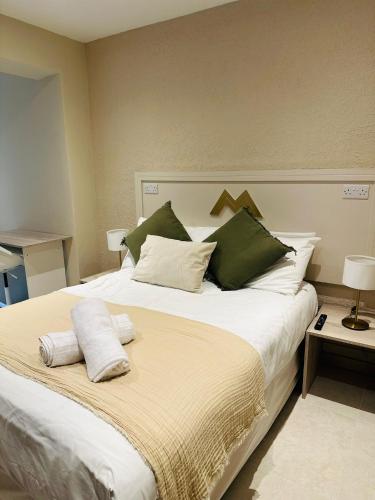a bedroom with a large bed with green and white pillows at MSM Arena Hotel in London