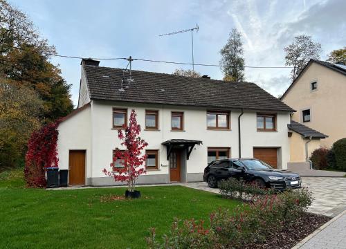 a white house with a car parked in front of it at Ferienhaus Naturtraum Eifel in Gerolstein