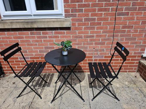 a black table with three chairs and a plant on it at Sotys Contractors, Long and Short term stays in Derby