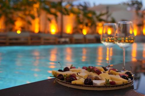 a plate of food and wine glasses next to a pool at Q Alaçatı Luxury Hotel in Cesme