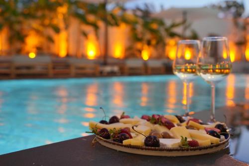 a plate of food and wine glasses next to a pool at Q Alaçatı Luxury Hotel in Cesme