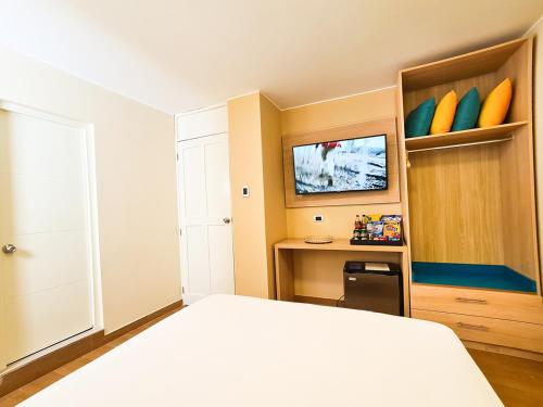 a bedroom with a bed and a desk and a tv at Acuario Hotel & Suite in Lima
