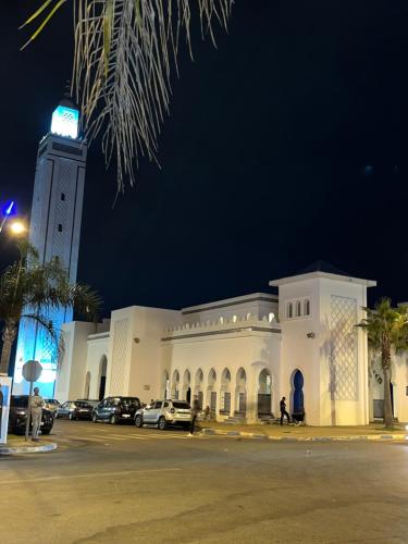 un grand bâtiment blanc avec une tour d'horloge la nuit dans l'établissement Shems Bouznika, à Bouznika