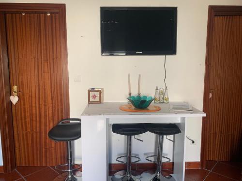 a kitchen with a bar with stools and a tv on the wall at Casinha in Quintela