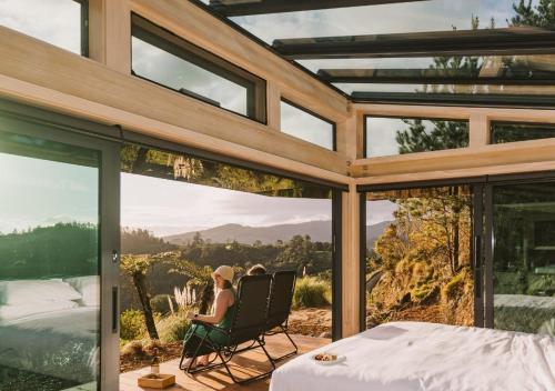 una donna seduta su una sedia su un patio con vista di Ruru PurePod a Waikino