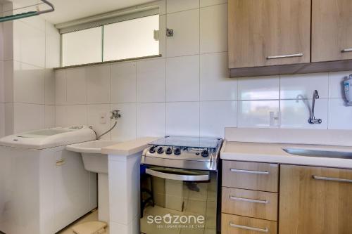 a white kitchen with a stove and a sink at Apto vista p/ rio c/ varanda - Pontal BCL402 in Ilhéus
