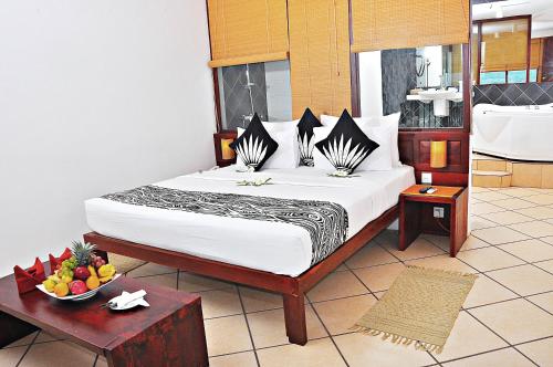 a bedroom with a bed and a bowl of fruit on a table at The Long Beach Resort & Spa in Koggala