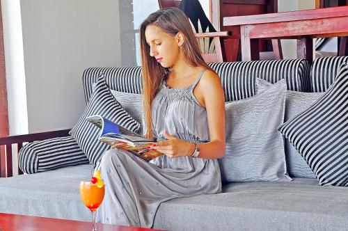 a woman sitting on a couch reading a book at The Long Beach Resort & Spa in Koggala