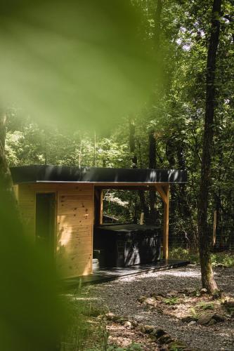 a wooden cabin in the woods with a black roof at Bérc Kabin Kismaros in Kismaros