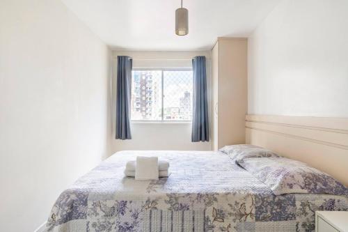 a bedroom with a large bed with a window at Apartamento a duas quadras da Praia Balneario Camboriu in Balneário Camboriú