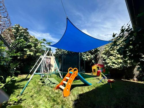 a playground with a blue canopy and a swing at Villa Tungara in Bejuco