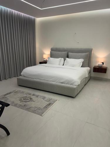 a white bedroom with a large bed with two lamps at Cove Chalet 1شاليه كوڤ in Al Ahsa