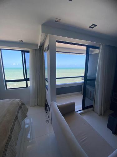 a bedroom with a couch and a view of the ocean at Golden Tower - Flat a Beira Mar in Natal