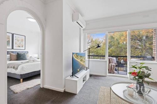 a white living room with a tv and a bed at Urban Oasis Prahran in Melbourne