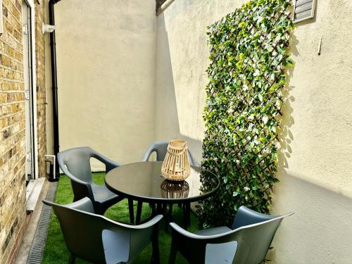 a table and chairs on a patio with a hedge at Westferry Two-Bedroom Deluxe Apartment in London