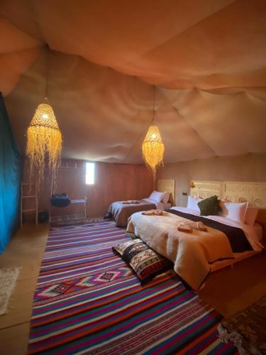 a bedroom with two beds in a tent at Pulse Desert Camp in Merzouga