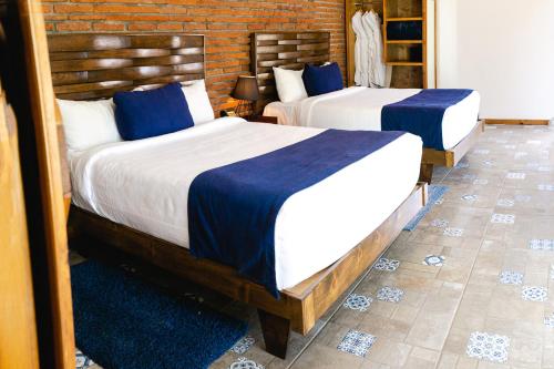 two beds in a hotel room with blue and white sheets at OJO AZUL RESORT in Valle de Guadalupe