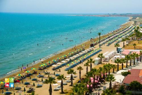 a beach with a lot of umbrellas and the ocean at Marina view seaside apartment in Larnaka