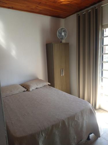 Pousada Nhá Chica في ساو ثومي داس ليتراس: غرفة نوم مع سرير وخزانة مع مروحة