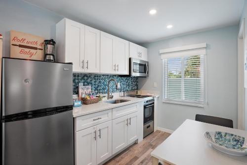 a kitchen with white cabinets and a stainless steel refrigerator at The Pearl Cabana Club in St Pete Beach