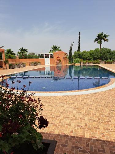a large swimming pool in a courtyard with trees at Atlas Garden Villa in Riaïna