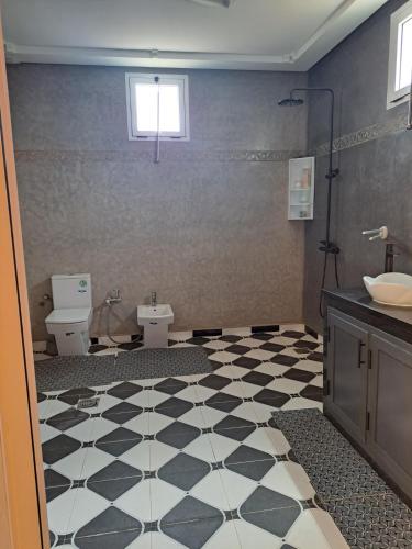 a bathroom with a black and white checkered floor at La Villa Olive in Riaïna