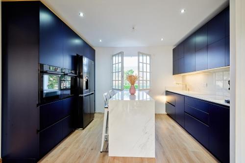 d'une cuisine avec des placards bleus et une table avec un vase. dans l'établissement Maison familiale Piscine & Spa, à Orsay