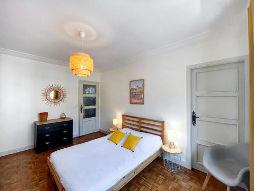 une chambre avec un lit blanc avec des oreillers jaunes dans l'établissement Le Chambellan, à Orléans