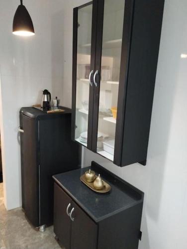 a bathroom with a black cabinet and a mirror at Lindo Loft no centro de Assis in Assis