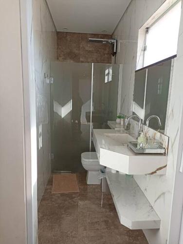 a bathroom with two sinks and a toilet and a shower at Lindo Loft no centro de Assis in Assis