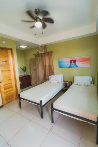 two beds in a room with a ceiling fan at Villa de Gloria in Dauis