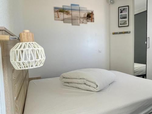 un lit avec un oreiller blanc et une lampe dans l'établissement Magnifique T2 climatisé avec terrasse à Canet-en-Roussillon - FR-1-748-7, à Canet
