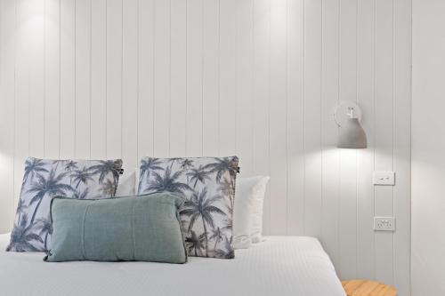 a bedroom with a bed with a pillow and palm trees at Fairshore Noosa in Noosa Heads