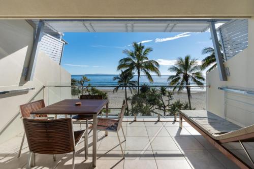 a balcony with a table and chairs and a view of the beach at Fairshore Noosa in Noosa Heads