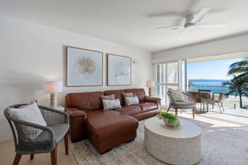 a living room with a brown leather couch and a table at Fairshore Noosa in Noosa Heads