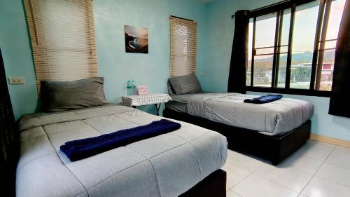 two beds in a room with blue walls and windows at โซพราว เขาค้อ So Proud Khaokho in Khao Kho