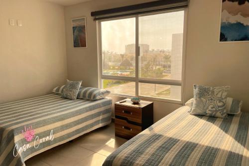 une chambre avec deux lits et une grande fenêtre dans l'établissement Depa Coral con Club de Playa Exclusivo Playa Bonfil Diamante, à Acapulco